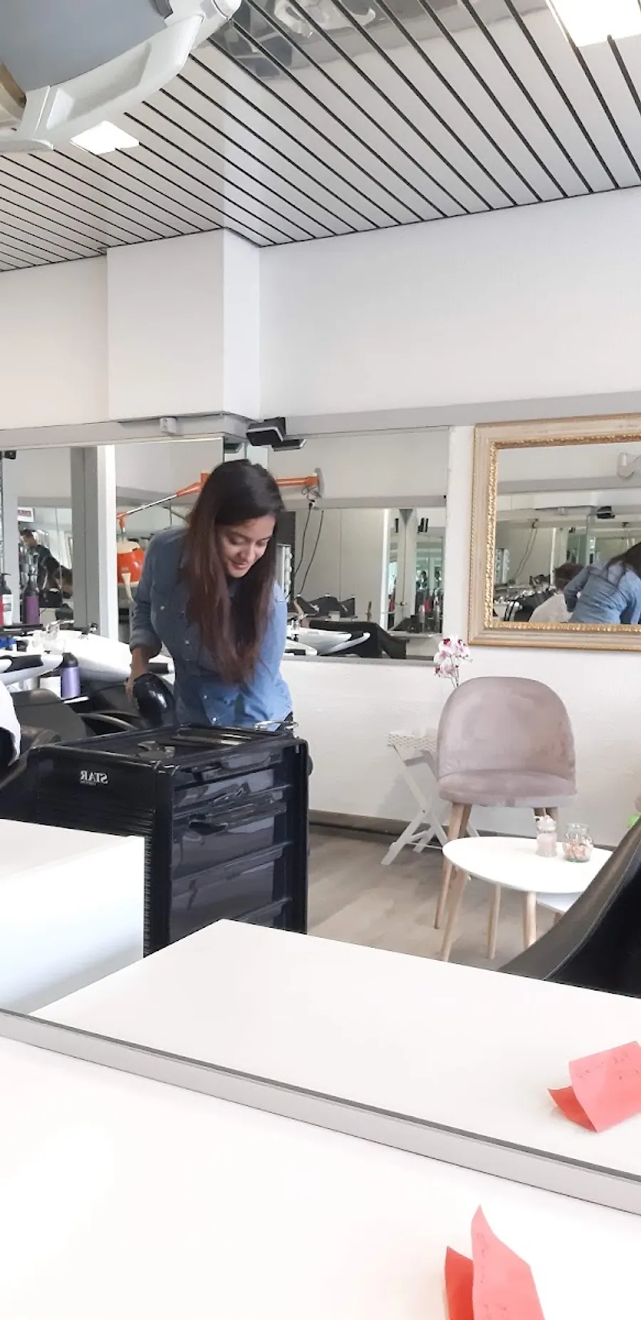 Intérieur du salon : plafond à lattes noires, miroir doré ancien et fauteuil en velours rose poudré